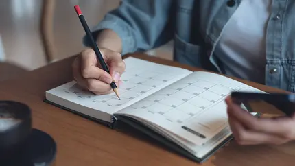 small buisiness owner flipping through calendar on desk, looking at key dates to focus on