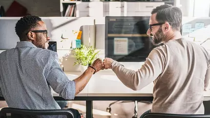 Two men at work fist bumping. start up. business partnership.