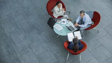 Two women and one man sitting in red chairs having a business conference. Benefits of business strategy and strategic management.