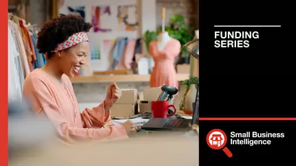 Black business woman smiling while sitting at her fashion shop.