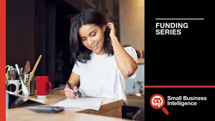 Businesswoman in white blouse fixing her hair while investigating merchant cash advances for her business.